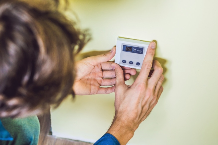 A person installing a thermostat