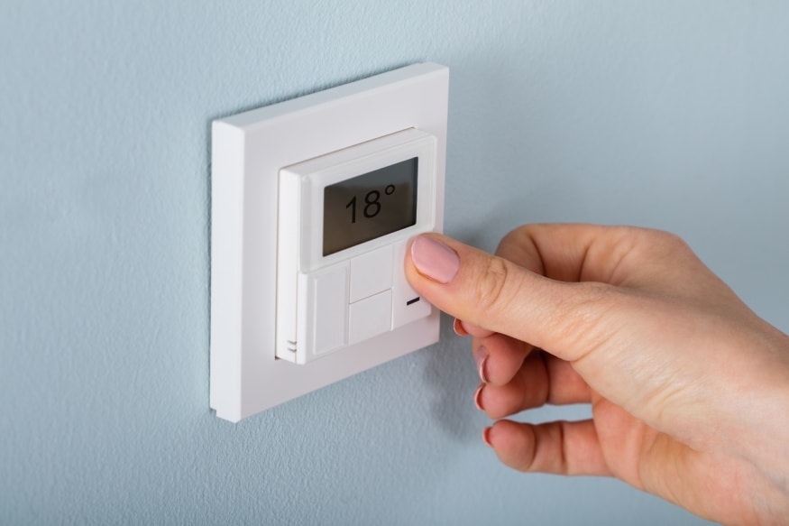 A hand adjusting the thermostat
