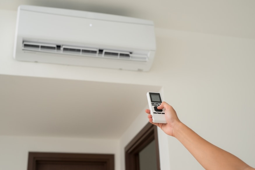 a person using the remote to set the AC’s temperature