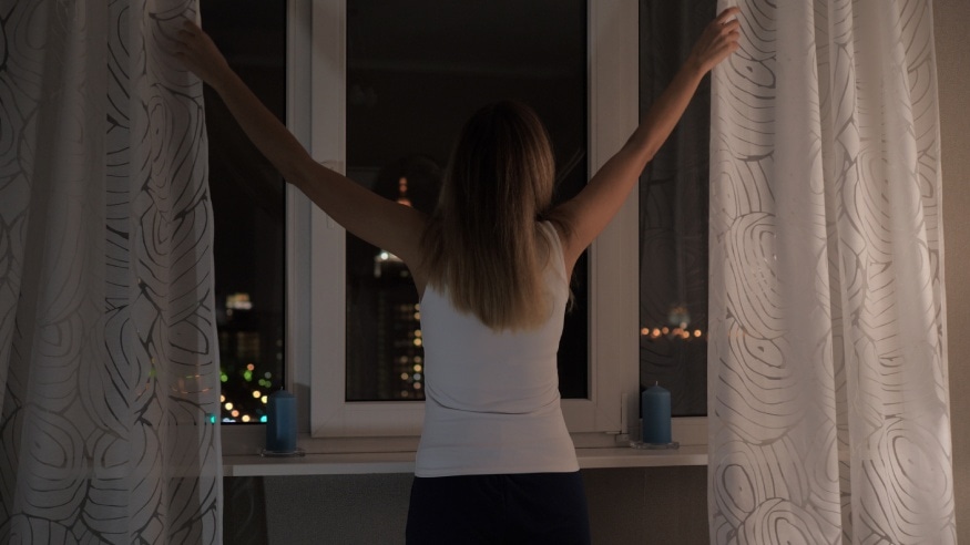 a woman closing the windows at night