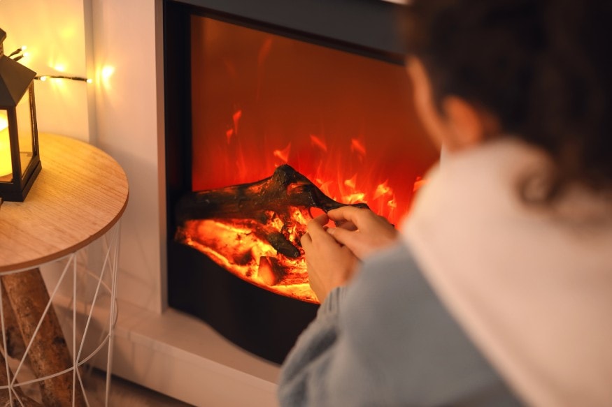 woman warming her hands at an electric fireplace
