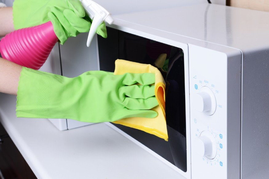 a person cleaning the microwave
