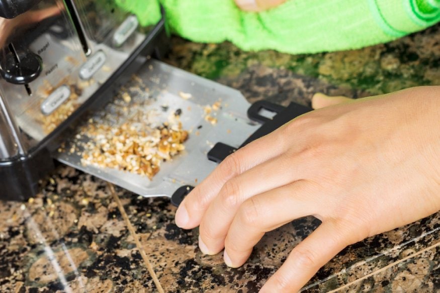 woman removing the bread crumb tray of the toaster